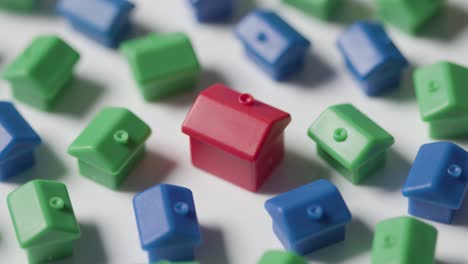 home buying concept with red blue and green plastic models of houses revolving on white background 1