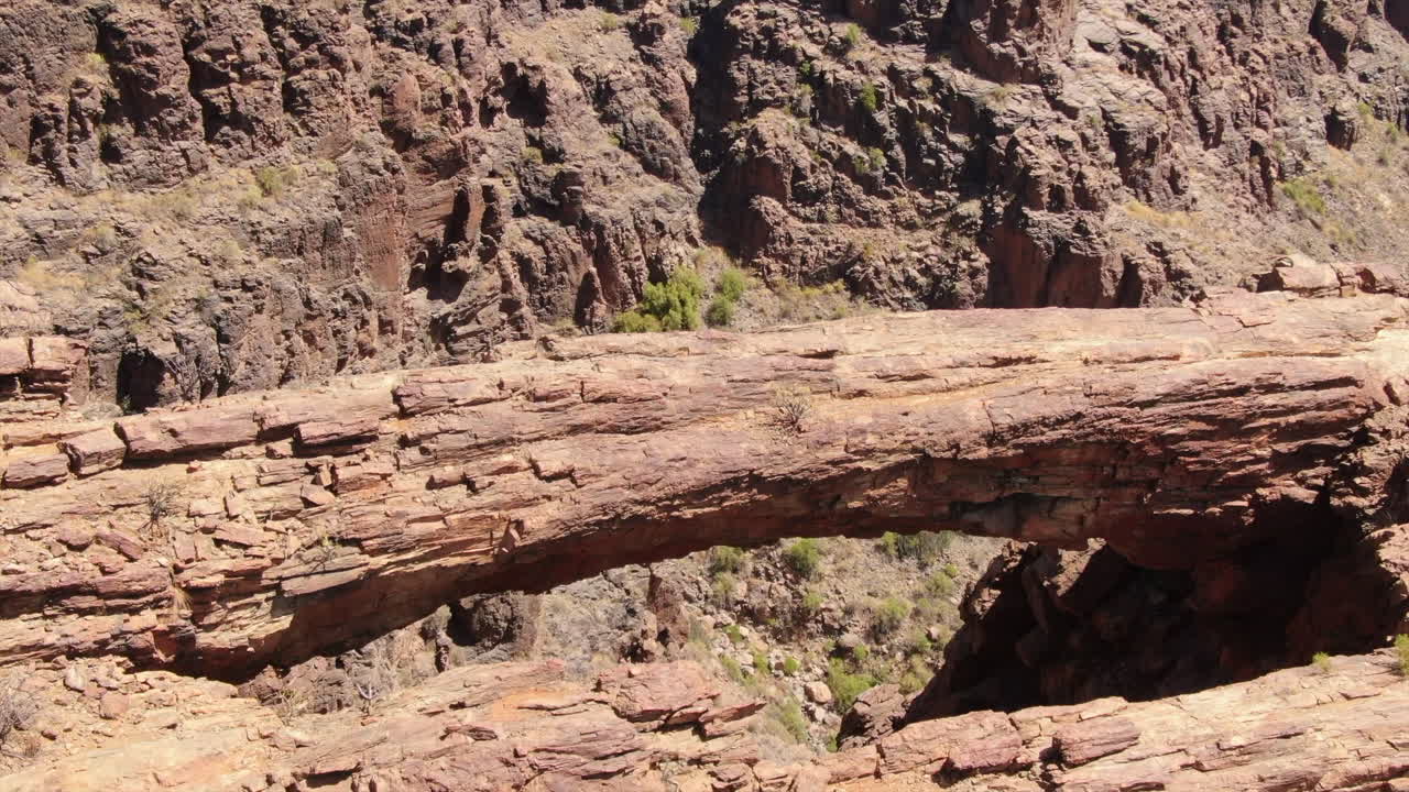 Aerial revealing view of Coronadero Arch in Gran Canaria: Spectacular natural rock formation, Coronadero Arch, revealed in a rugged canyon on a sunny day