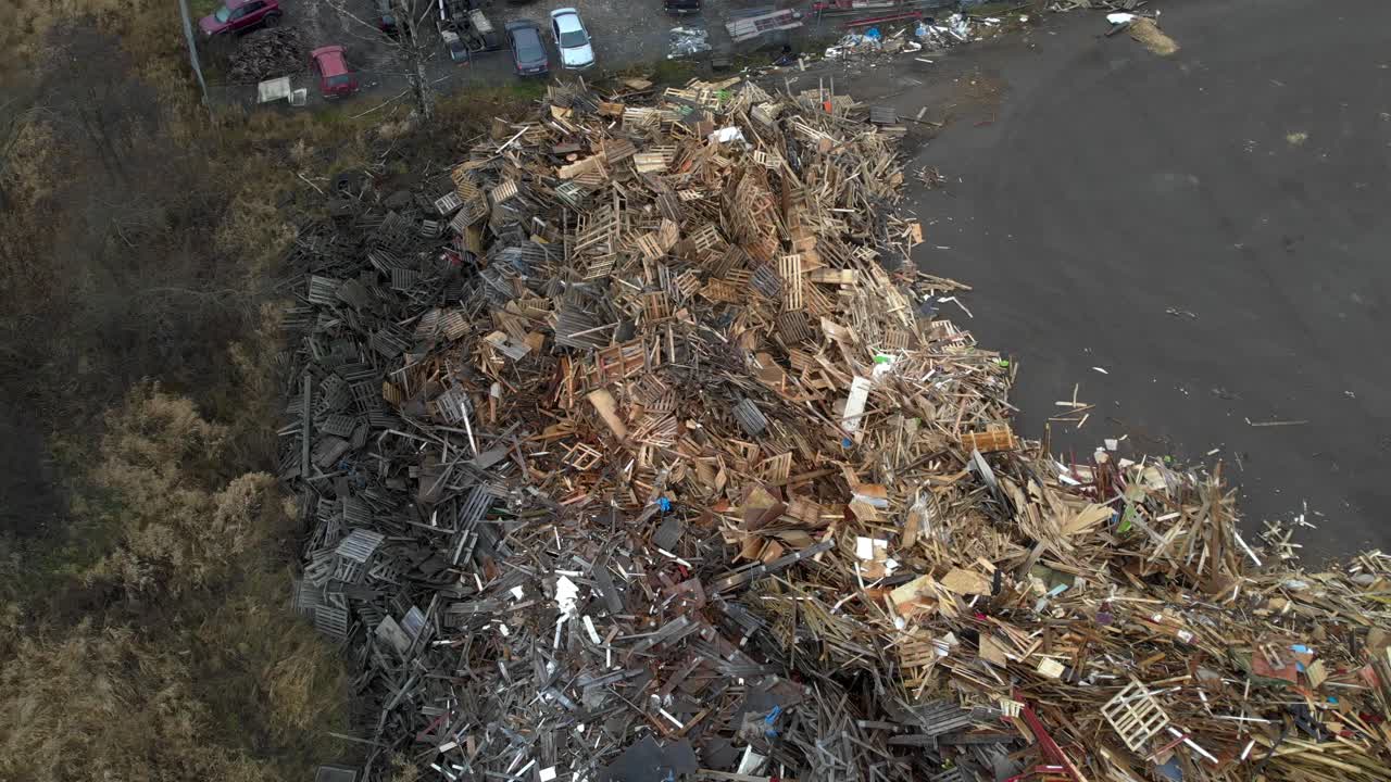 vista aérea de arriba hacia abajo girando sobre un enorme basurero lleno de montones de residuos voluminosos y de madera hechos de paletas europeas claras y oscuras