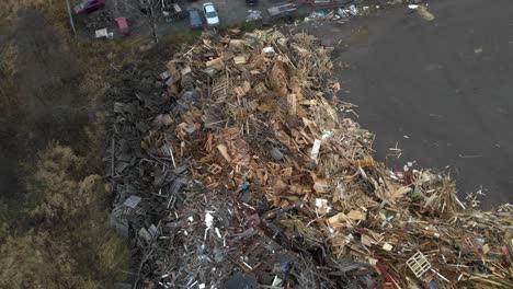 aerial top down view rotating over huge dumpsite filled with pile of wooden and bulky waste made up of light and dark euro pallets