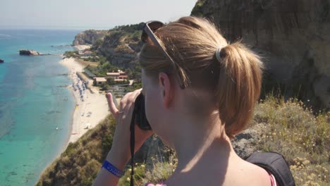 Mujer-En-Un-Acantilado-Está-Tomando-Fotos-De-La-Playa