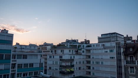 blue sky with bright white sun rising above cluster of european short high-rise buildings, time lapse sunrise