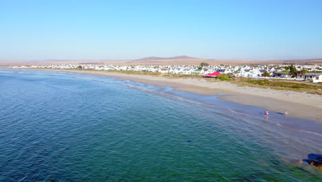 Tourists-stroll-on-scenic-stretch-of-beach-in-Paternoster,-South-Africa