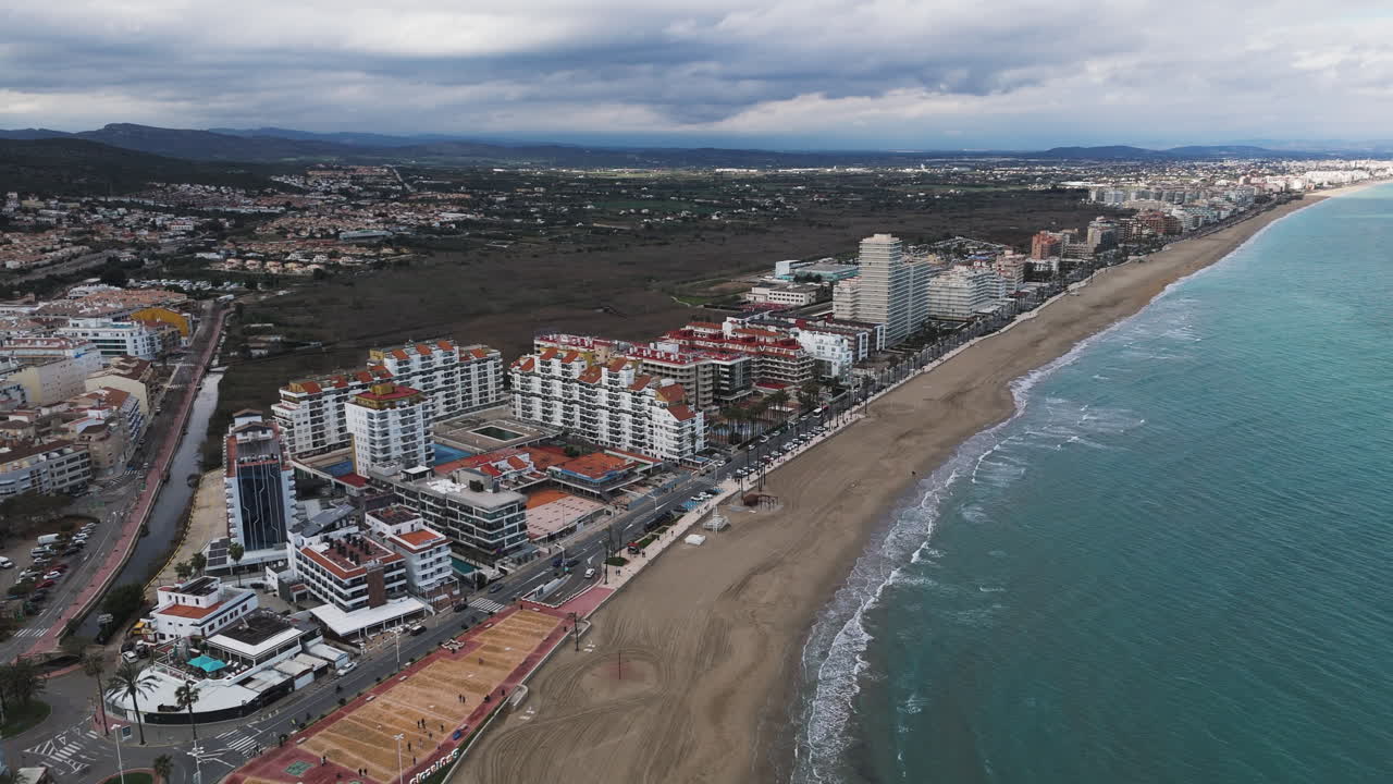 Long vertical tilt over Peniscola beachfront showing full skyline and curved coastline
