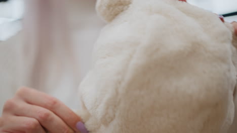 hand view expectant mother feeling soft wool winter cloth in baby section of store, testing plush fabric texture, pastel garments blurred in background under warm lighting