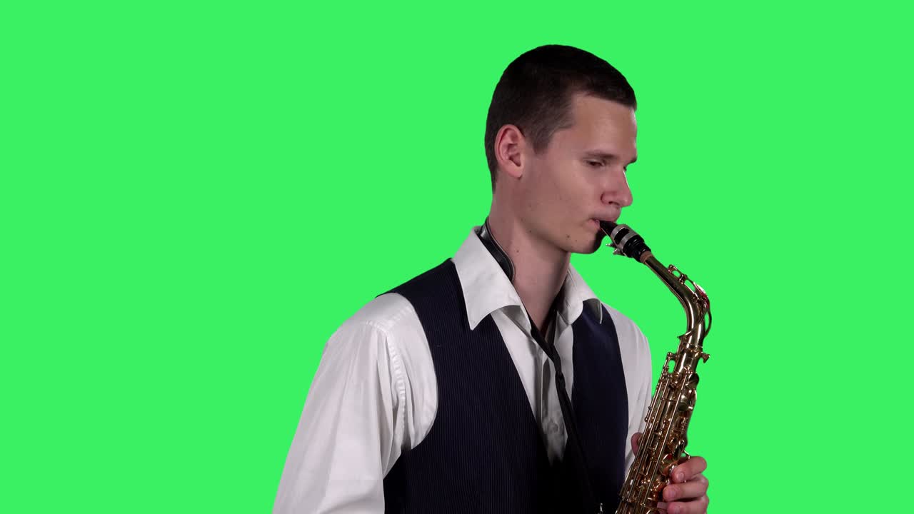 Ritratto di giovane elegante che suona una melodia al sassofono su schermo verde in studio. Sassofonista che esegue un assolo. Primo piano. Vista laterale