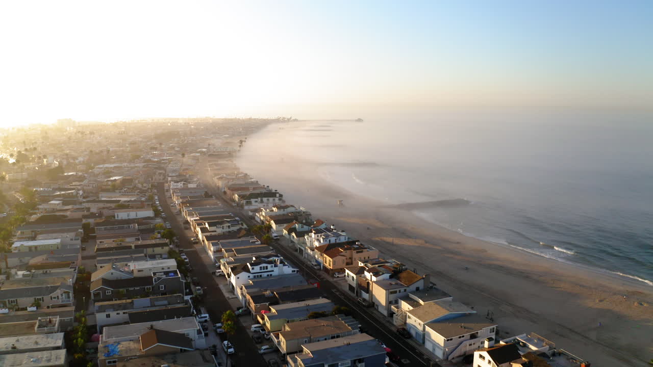 Aerial View of a Coastal Town and Foggy Beach at Sunrise or Sunset