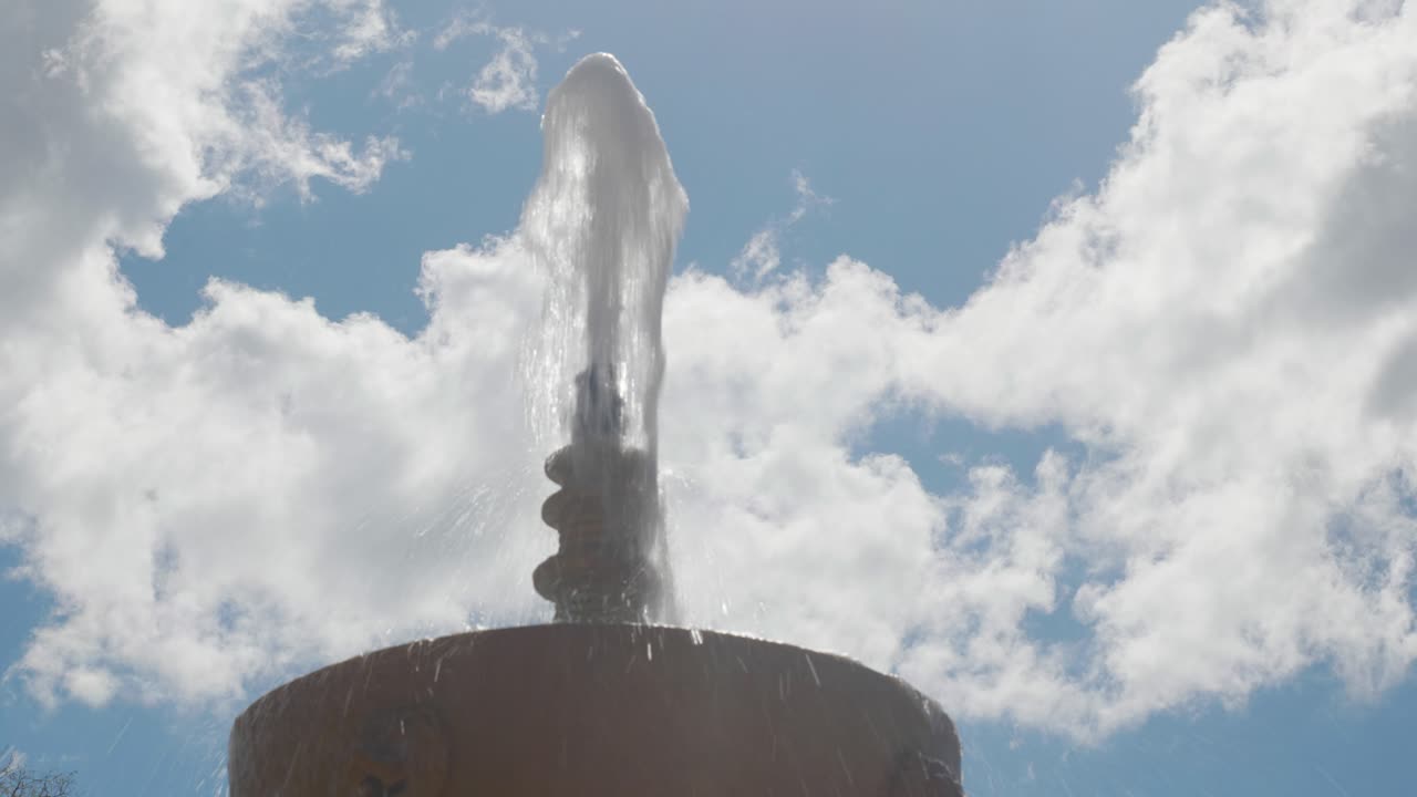 fuente de piedra con un chorro de agua en un día nublado