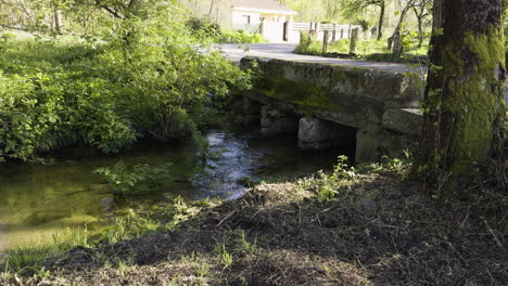 el agua fluye lentamente por debajo de la calma de un puente de carretera de campo vacío en galicia, españa.