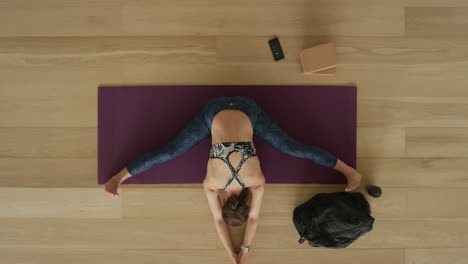 overhead view flexible yoga woman practicing wide-angle seated forward bend pose enjoying healthy lifestyle exercising in fitness studio training on exercise mat