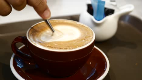 Person-hand-stirring-coffee-with-spoon