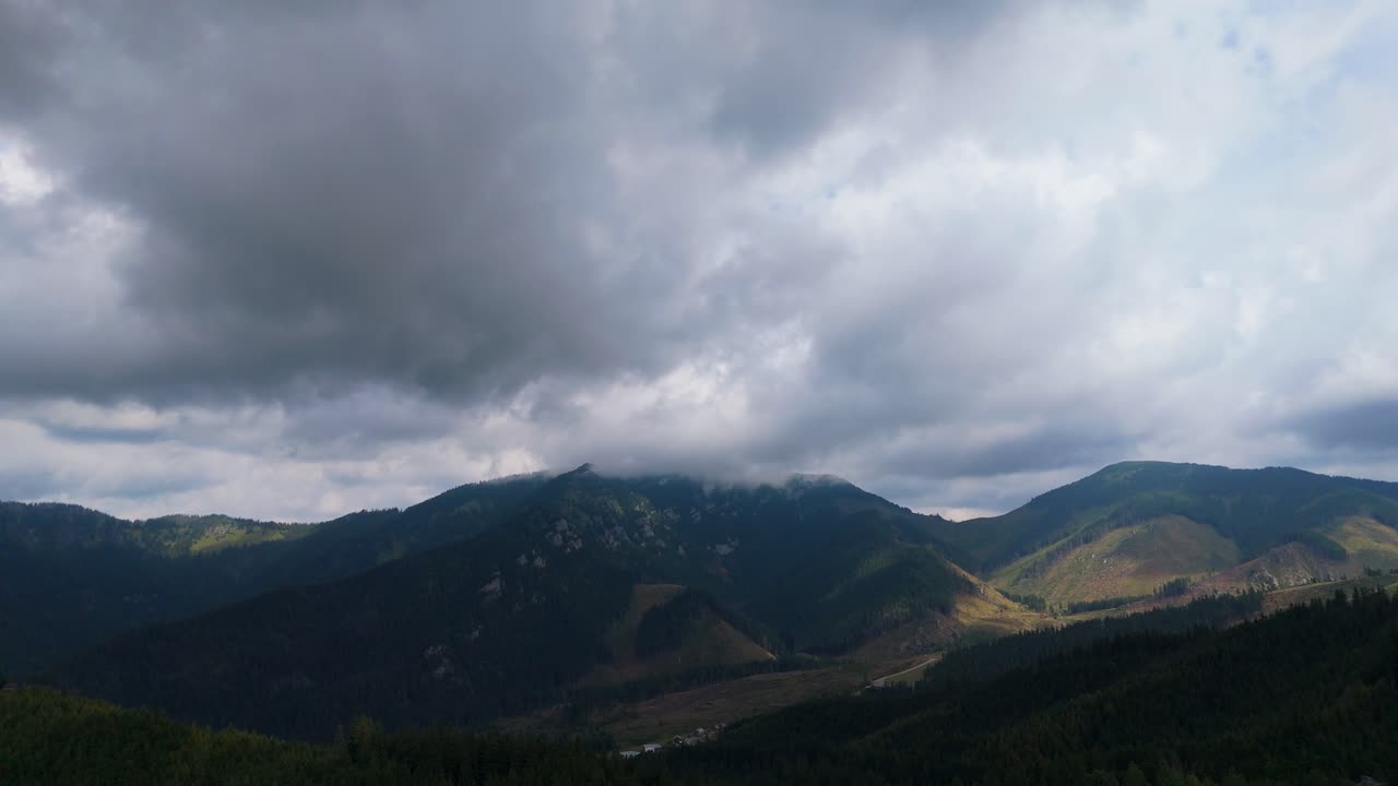 Aerial footage of mountain peaks near Zakopane, Poland, in summer. Lush green landscape with drifting clouds over alpine scenery. Ideal for nature, travel, and outdoor visuals