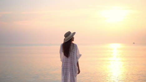 Una-Mujer-Joven-Se-Encuentra-En-La-Playa-Al-Atardecer-Viendo-Las-Olas-Entrar