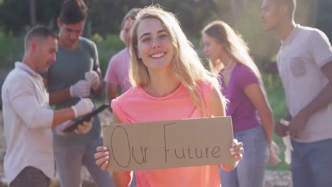 Mid-adult-smiling-and-looking-at-camera-with-woman-holding-Our-Future-sign-during-river-clean-up-day