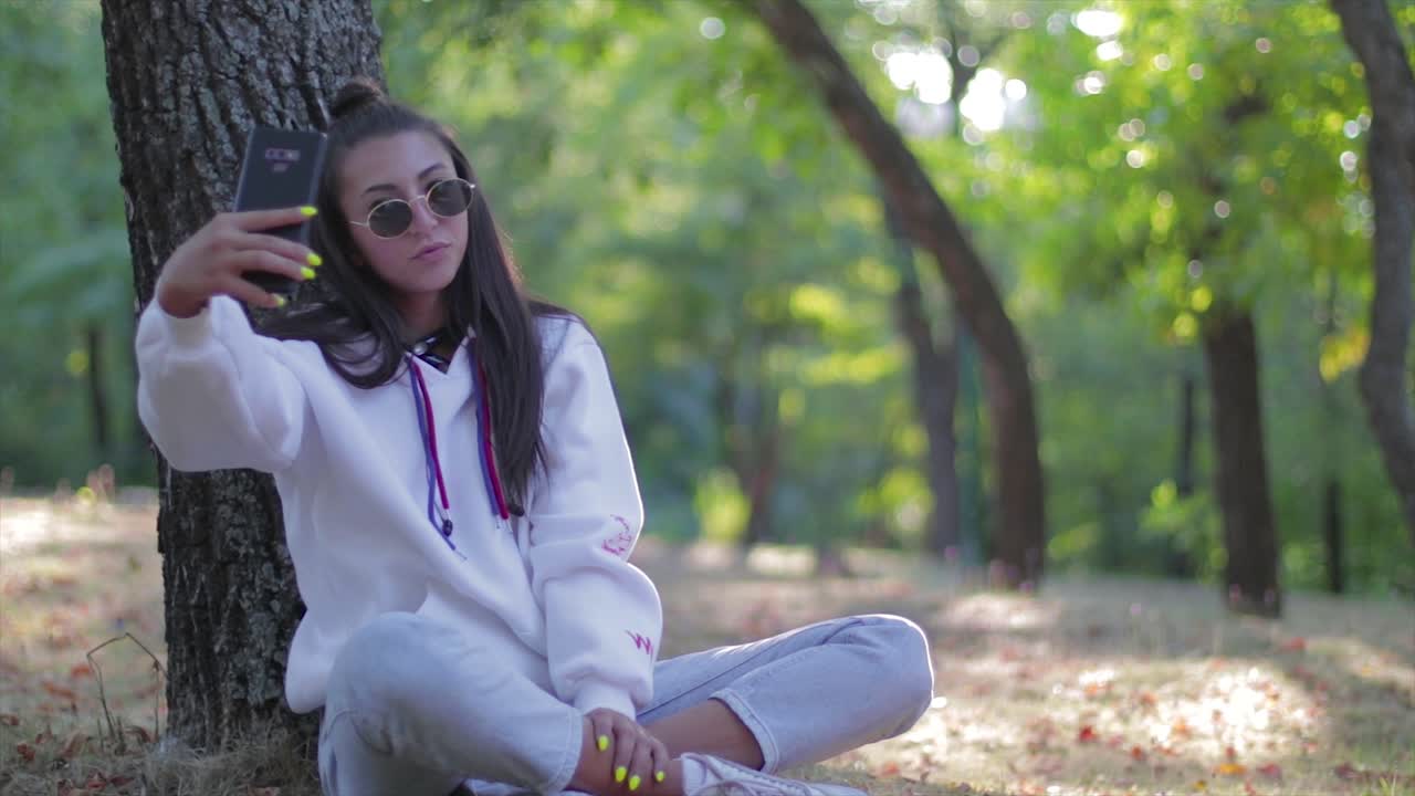 chica tomando una selfie con un teléfono en un parque