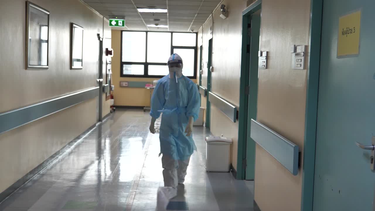 medico che indossa dpi completo che cammina nel corridoio dell'ospedale covid-19