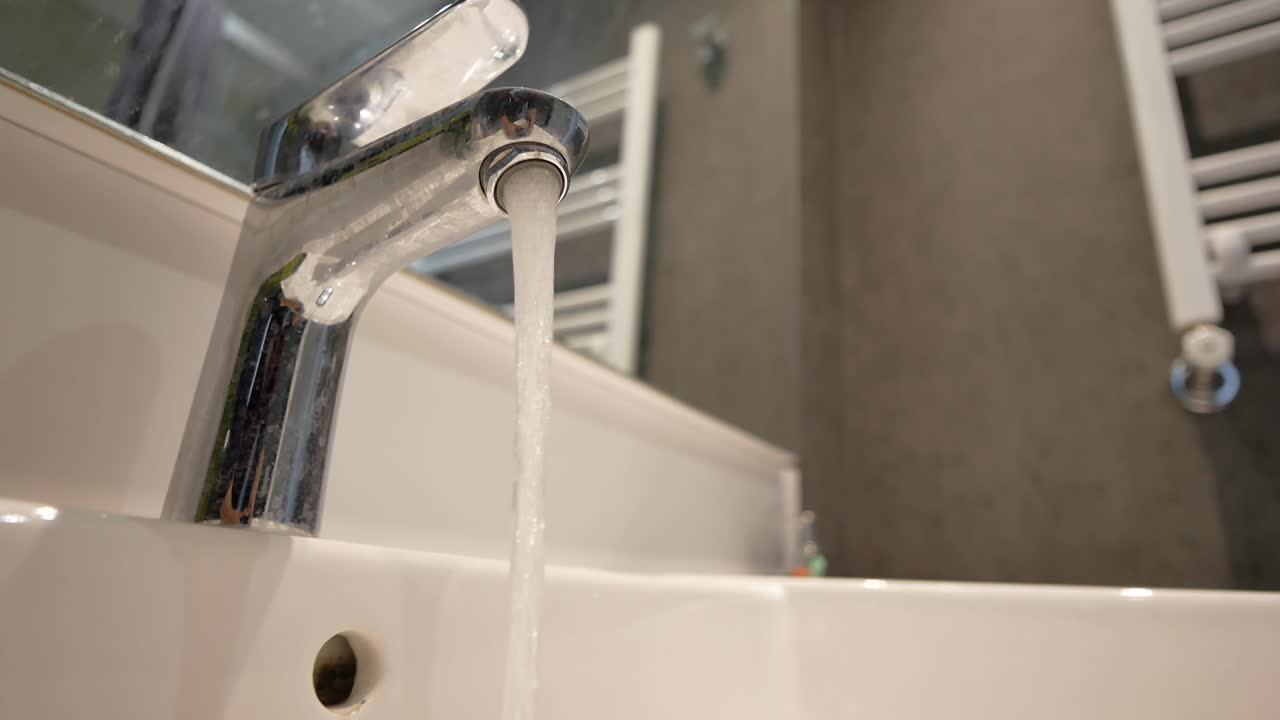 Acqua che gocciola dal rubinetto della cucina, primo piano, filmato 4K di alta qualità