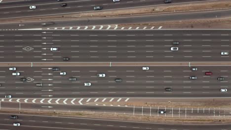 drone view from above of a large highway with several lanes on which many cars are driving, going about their routine