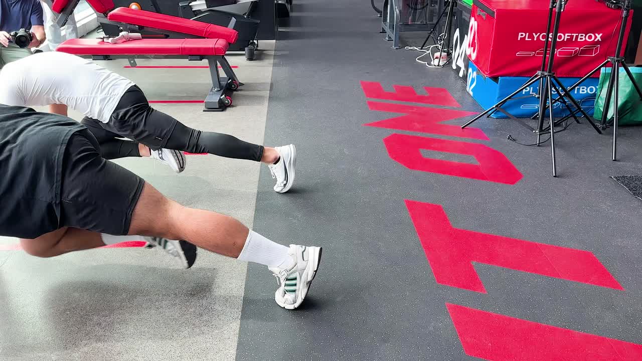Athlete executes mountain climbers on gym floor, bright lighting, stable camera, energetic fitness atmosphere