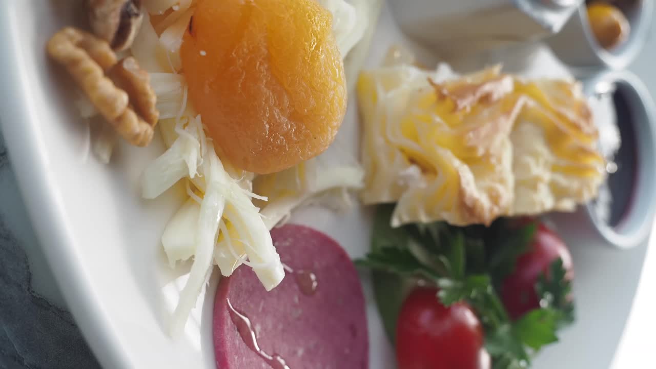 Assorted cheeses, walnuts, and dried apricots on a plate