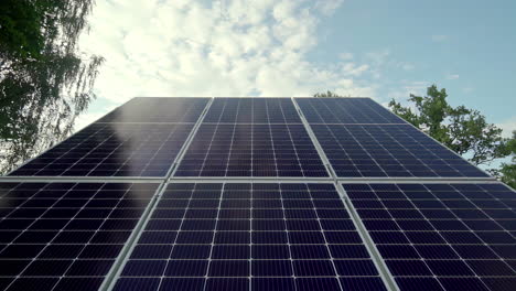 Low-angle-trucking-shot-of-a-large-solar-panel-pointing-to-a-cloudy-sky