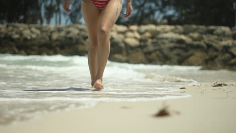 mujer en bikini rojo caminando por una playa en australia