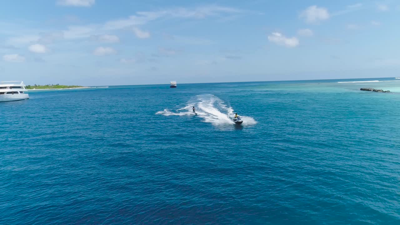 Inseguimento con drone su un uomo che guida una moto d'acqua in un'isola esotica paradisiaca tropicale con vista sull'oceano blu e turchese. Concetto di avventura per attrazione turistica per sport da vacanza in spiaggia in una giornata estiva