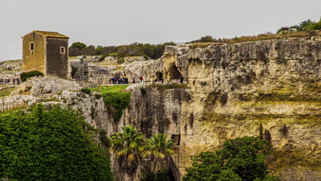 people at latomie del paradiso - historical ancient quarry with caverns in syracuse, italy