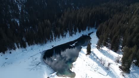 vista aérea del tranquilo lago caumasee rodeado de nieve blanca y árboles de coníferas