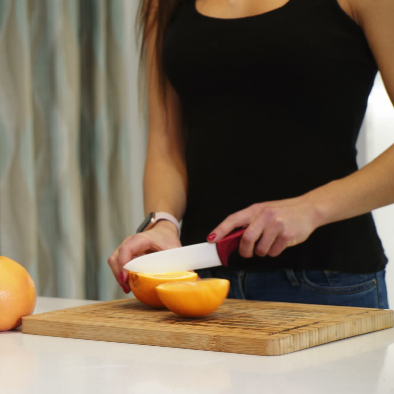 Female hands cutting orange on a wooden board. Woman in the kitchen. Healthy eating. Raw food. Square video