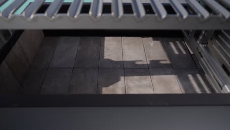 close up of an empty metal brasero barbecue grill interior with tiled base and steel grate above