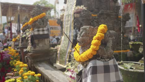 balinese temple statues with marigold offerings and incense