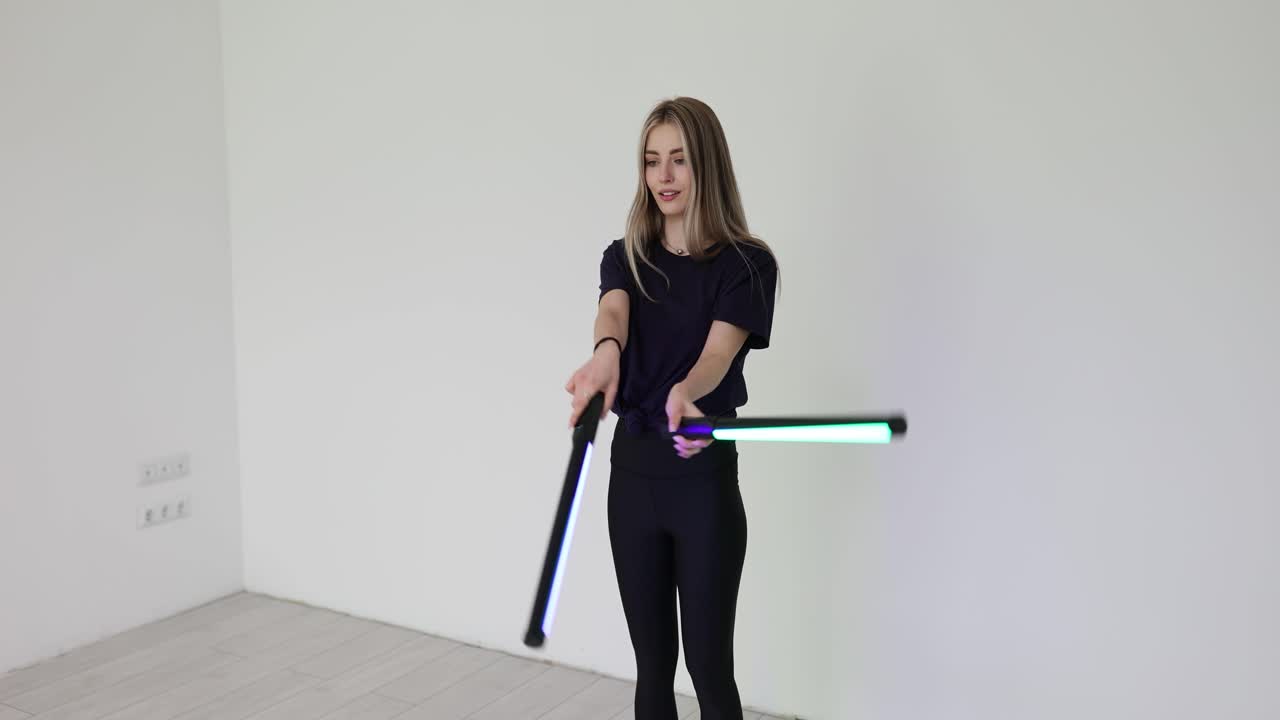 Young Woman Posing with LED Light Tubes in a Studio