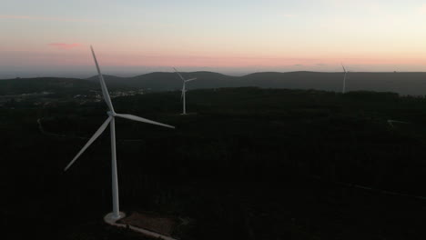 Hermosas-Turbinas-Eólicas-Giratorias-Al-Atardecer-En-Serra-De-Aire-Y-Candeeiros-En-El-Distrito-De-Leiria,-Portugal---Toma-Aérea-De-Drones