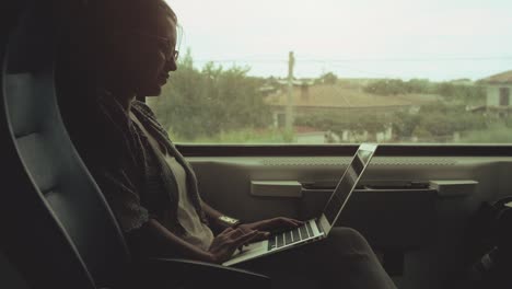 young woman with glasses using laptop on moving train