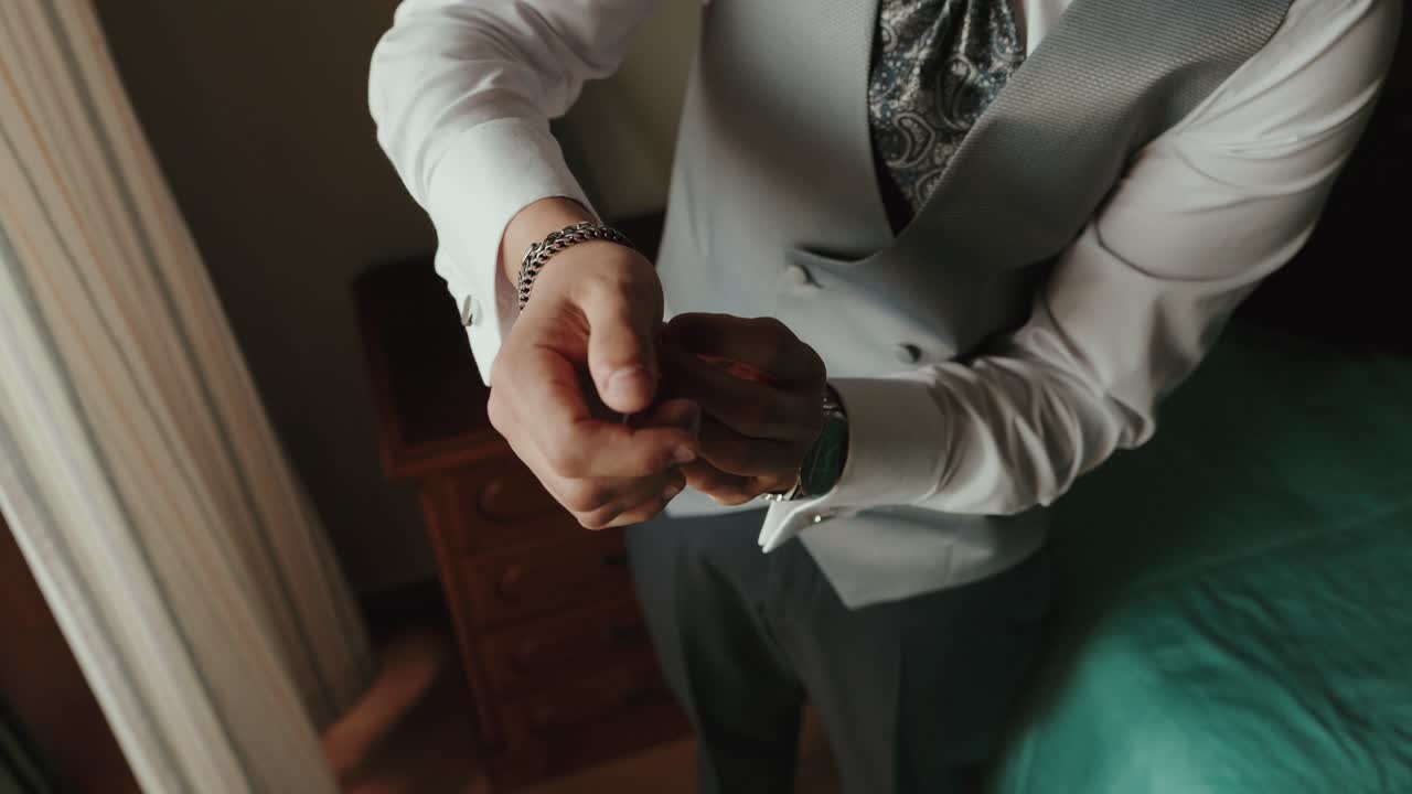 groom prepares suit with cufflinks in soft daylight indoors