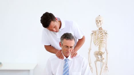 physiotherapist giving businessman a shoulder massage