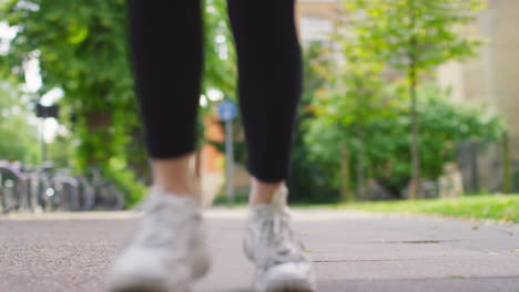 Ground-Level-Shot-Of-Young-Woman-Exercising-Running-Towards-Camera-Into-Focus-In-City-Park