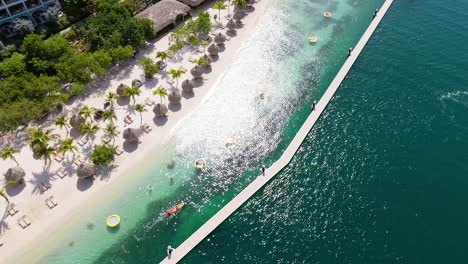 Sunlight-glistens-on-ocean-light-as-floating-lily-pads-relax-in-ocean-on-inside-of-pier-dock-at-Sandals-Beach-resort