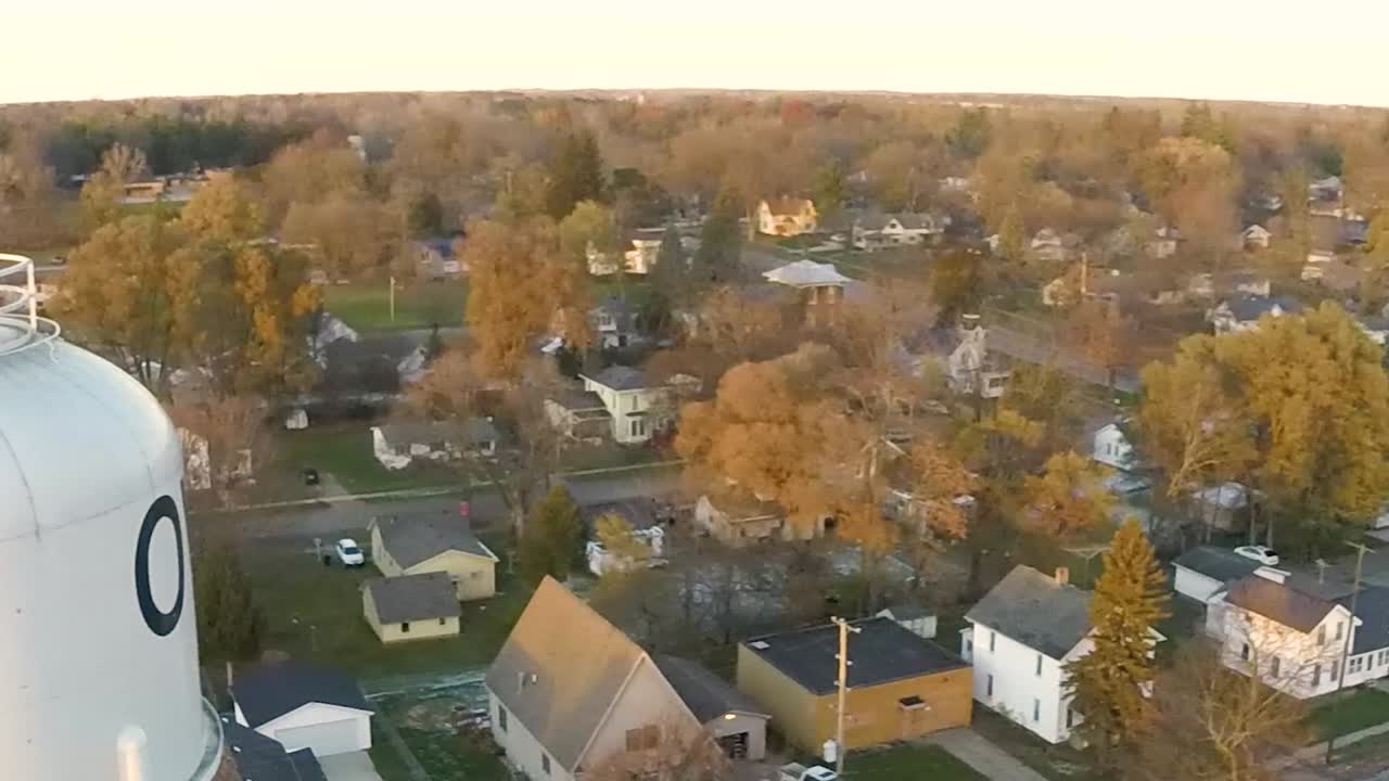 Aerial drone shot next to a water tower panning right in the small town of Ovid, Michigan at sunset