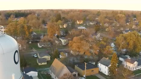aerial drone shot next to a water tower panning right in the small town of ovid, michigan at sunset