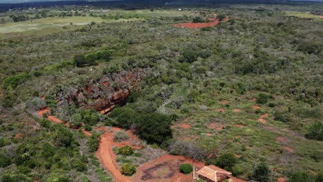 aerial drone rising and tilting down medium shot of the lapa doce cave entrance with a self-contained rainforest below in the chapada diamantina national park in bahia, northeastern brazil