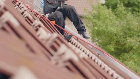 knee level view of worker installing solar panel on top of rooftop, day