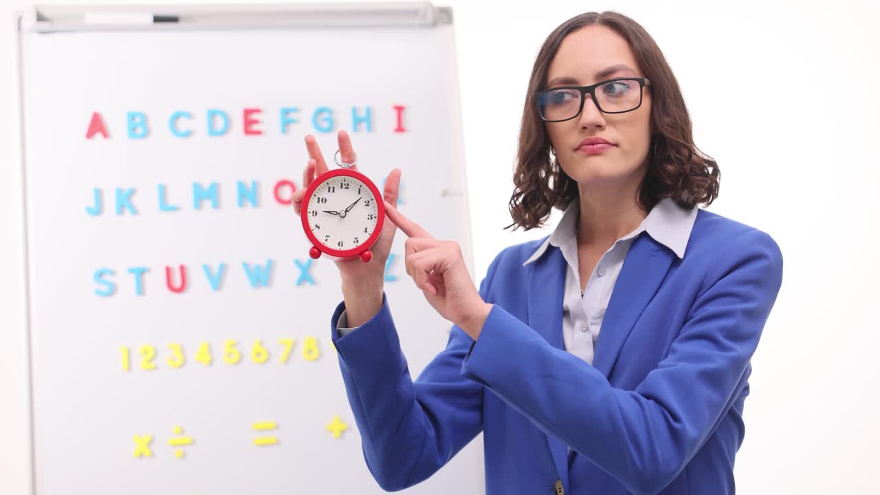 Female Teacher Holding an Alarm Clock in a Classroom