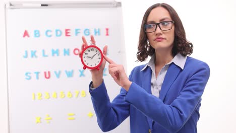 female teacher holding an alarm clock in a classroom