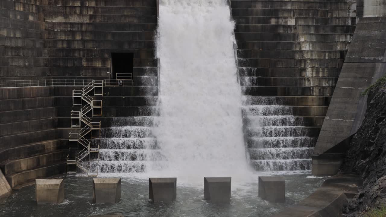 Medium view of water flowing through the Hinze Dam overflow and dam steps due to ongoing heavy rains in the Gold Coast Hinterland