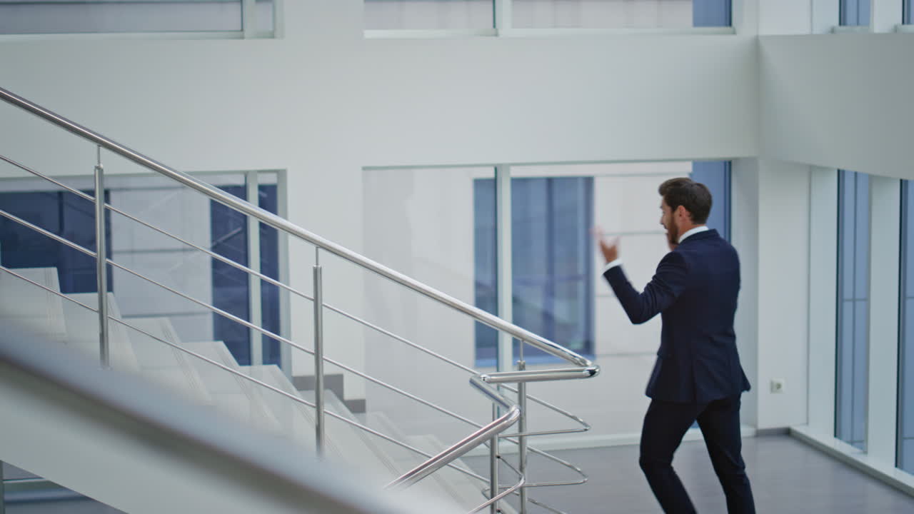 Businessman talking cellphone climbing office stairs. Corporate manager calling