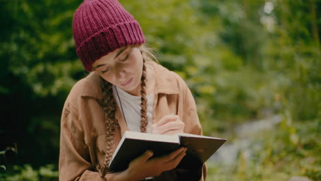 mujer con cabello trenzado escribiendo en un libro