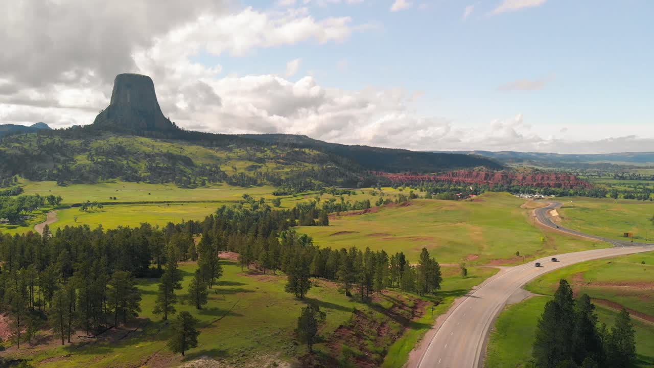 Aerial shot of Devils tower, forest and street. Devil's Tower National Monument in Wyoming. 4K drone video pull out shot. Devils Tower Butte and Belle Fourche River in Sunny Autumn Morning.