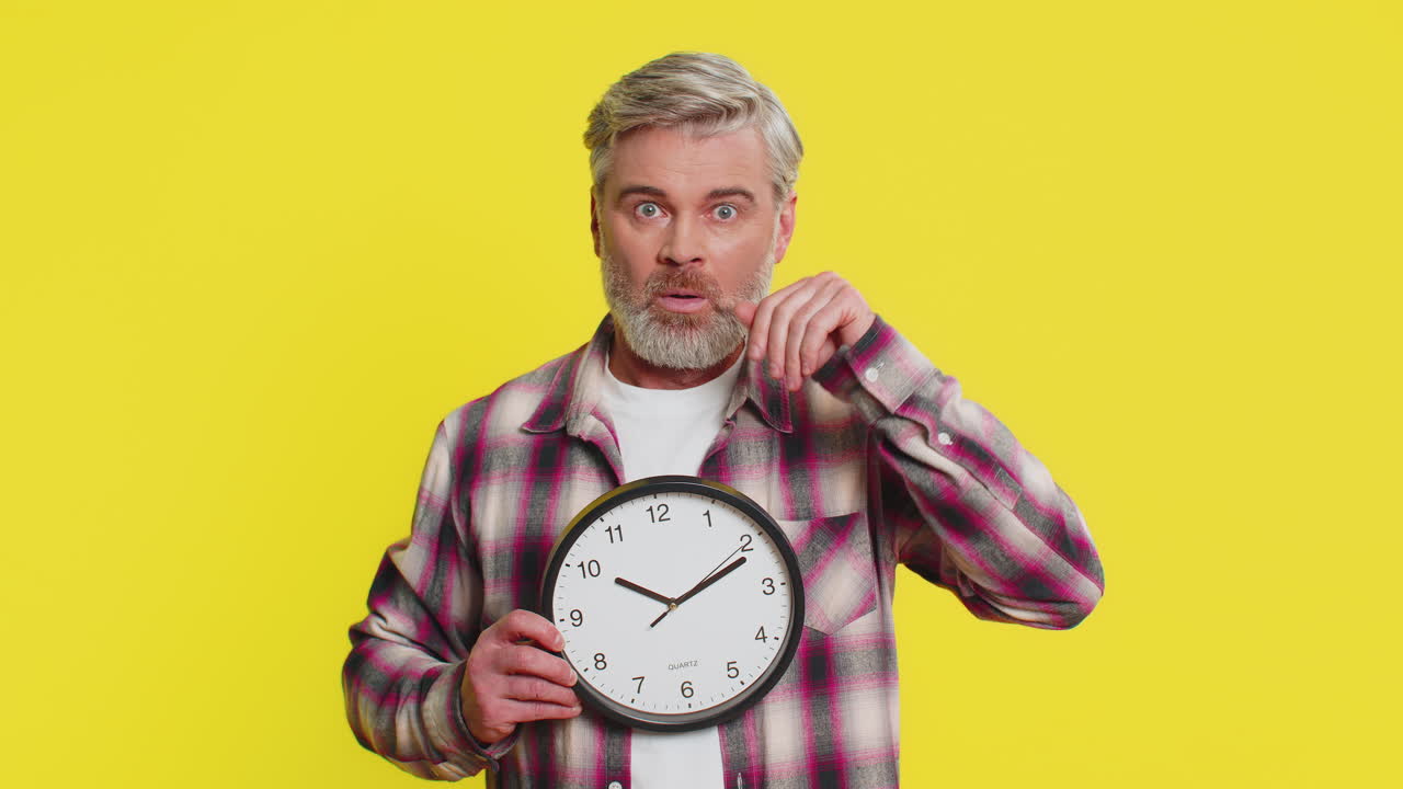 Mature man holding big office clock urgent deadline sign anxious lateness gesture time pressure
